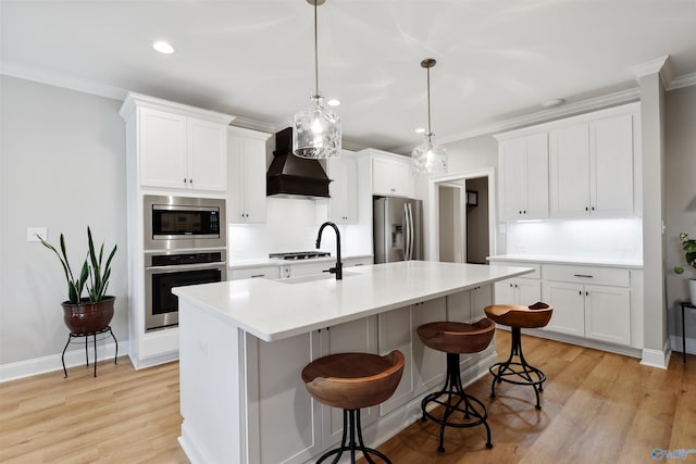 kitchen with stainless steel appliances, white cabinetry, custom range hood, and sink