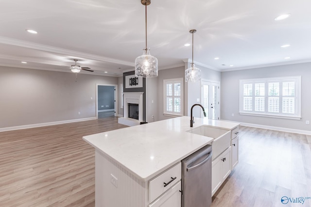 kitchen featuring pendant lighting, sink, dishwasher, a kitchen island with sink, and white cabinetry