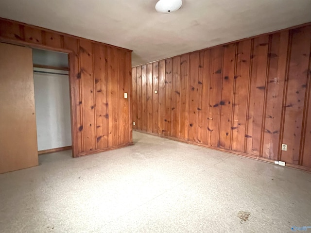 unfurnished bedroom with a closet and wood walls