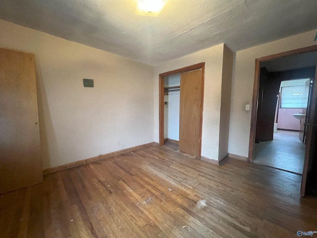 unfurnished bedroom featuring wood-type flooring, a textured ceiling, and a closet