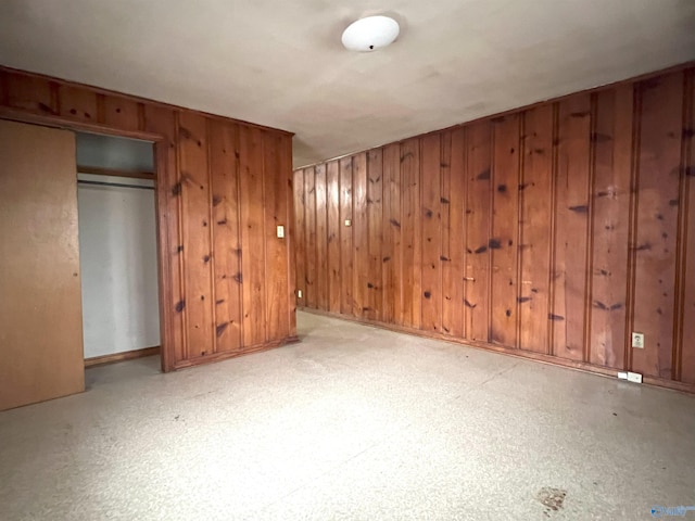 unfurnished bedroom with a closet and wood walls