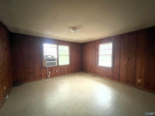 spare room featuring cooling unit, a healthy amount of sunlight, and wood walls