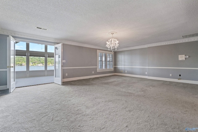 spare room featuring ornamental molding, carpet floors, a textured ceiling, and a chandelier