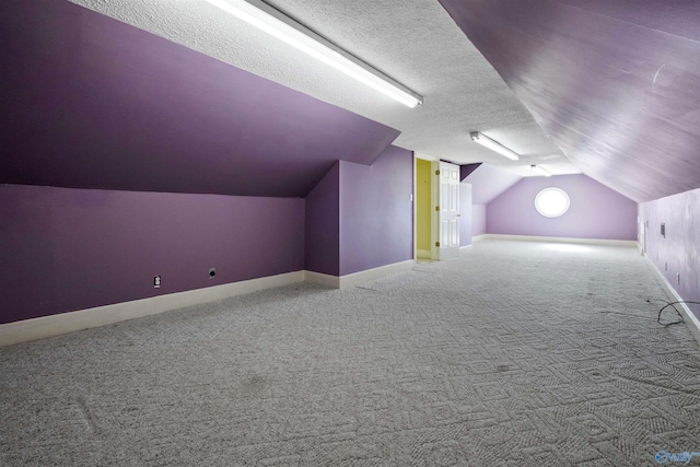 additional living space featuring carpet, a textured ceiling, and vaulted ceiling