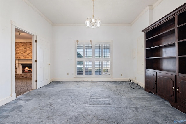 unfurnished living room with crown molding, a fireplace, a notable chandelier, and carpet