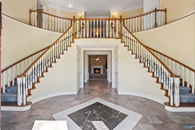 tiled foyer featuring ornamental molding, a large fireplace, and a high ceiling