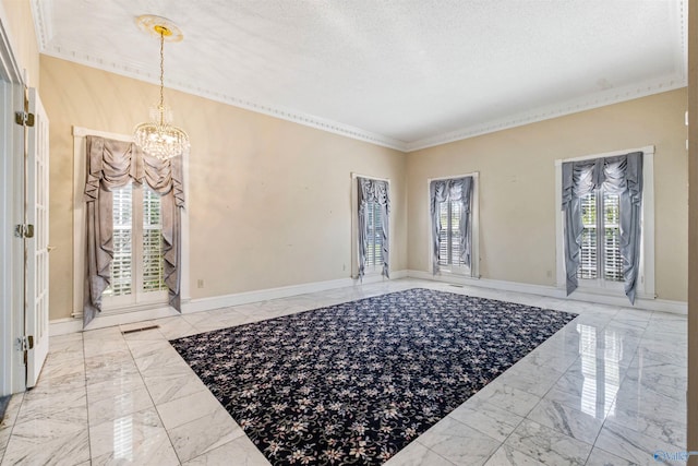 tiled foyer with a healthy amount of sunlight, a textured ceiling, a notable chandelier, and ornamental molding