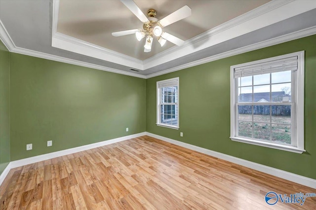 unfurnished room featuring a raised ceiling, ceiling fan, light hardwood / wood-style flooring, and ornamental molding