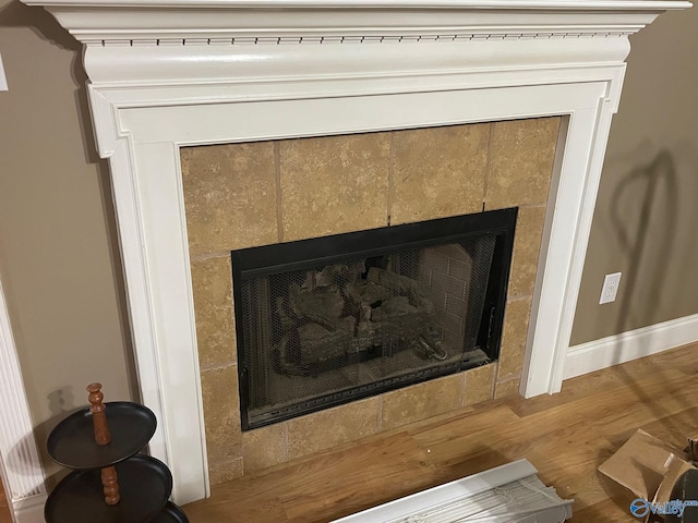 interior details featuring a tiled fireplace and hardwood / wood-style flooring