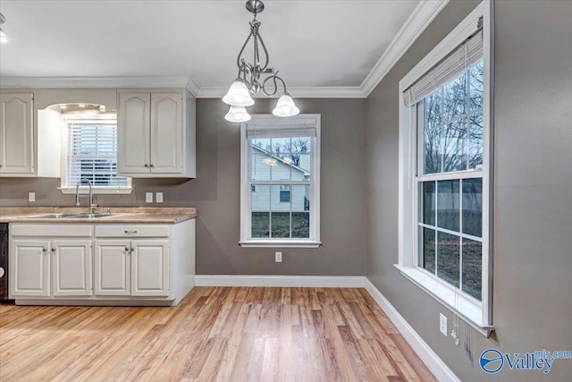 kitchen featuring crown molding, sink, an inviting chandelier, white cabinetry, and hanging light fixtures