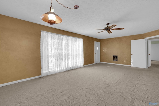 empty room featuring carpet flooring, a textured ceiling, heating unit, and ceiling fan