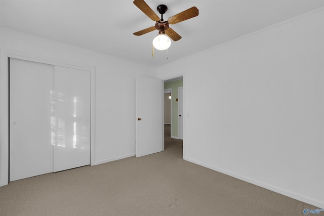 unfurnished bedroom with ceiling fan, crown molding, light carpet, and a closet