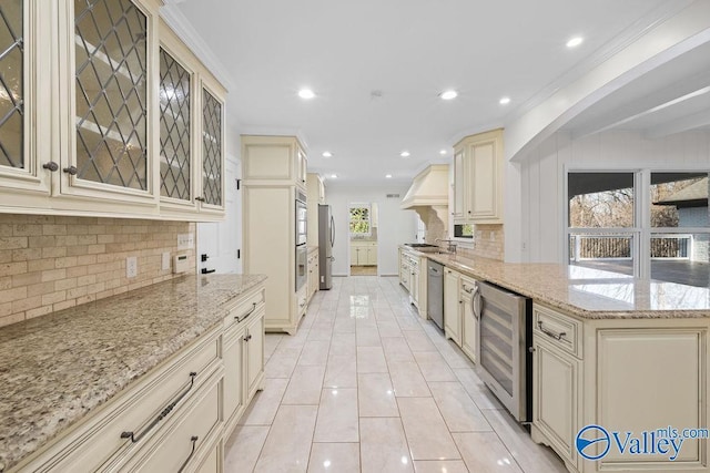 kitchen featuring appliances with stainless steel finishes, light stone counters, beverage cooler, and cream cabinets