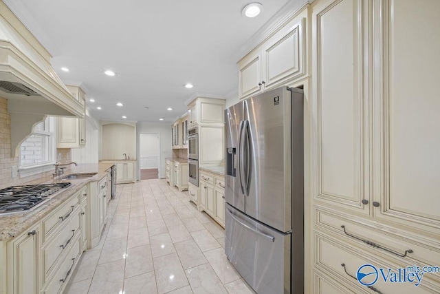 kitchen with light stone countertops, appliances with stainless steel finishes, tasteful backsplash, sink, and cream cabinets