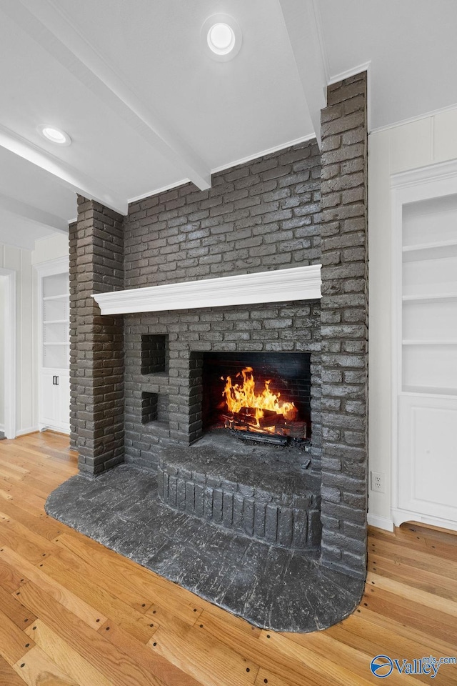 details with a fireplace, wood-type flooring, built in features, and beamed ceiling