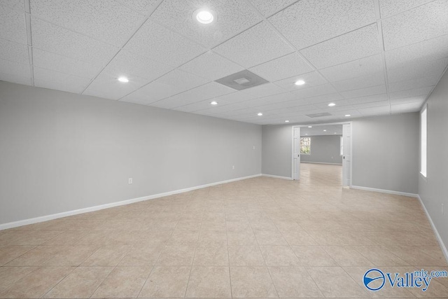 basement featuring a drop ceiling and light tile patterned floors