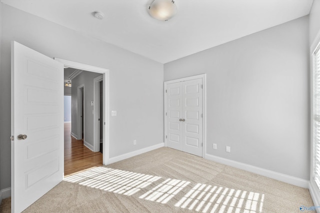 unfurnished bedroom featuring light carpet and a closet