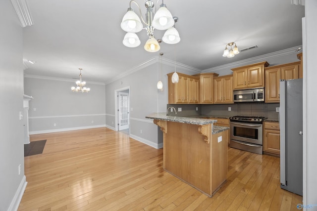 kitchen featuring a kitchen bar, appliances with stainless steel finishes, light wood-type flooring, light stone counters, and an inviting chandelier