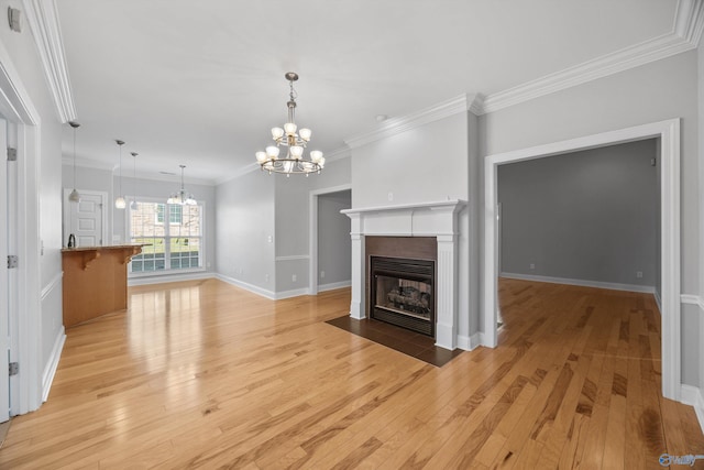 unfurnished living room with an inviting chandelier, ornamental molding, and light hardwood / wood-style flooring