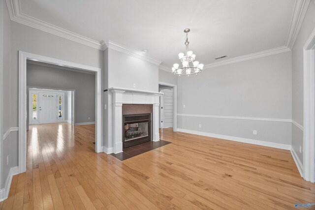 unfurnished living room with crown molding, wood-type flooring, and an inviting chandelier