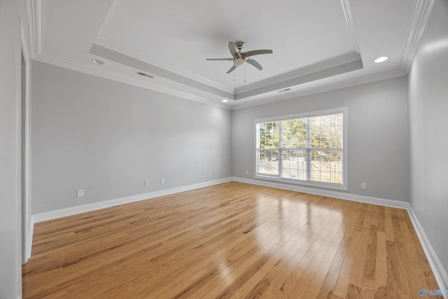 empty room with a raised ceiling, light hardwood / wood-style flooring, ceiling fan, and ornamental molding