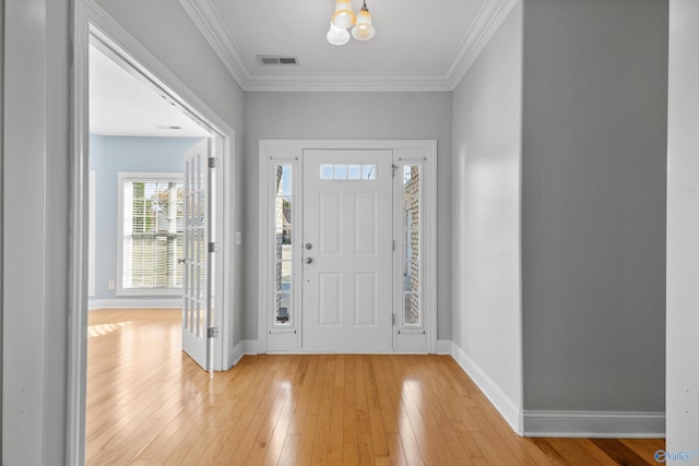 foyer entrance with ornamental molding, a notable chandelier, and light wood-type flooring