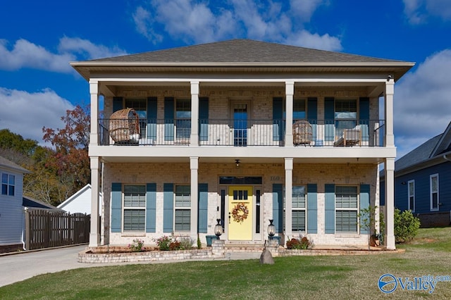 view of front of house featuring a balcony and a front lawn