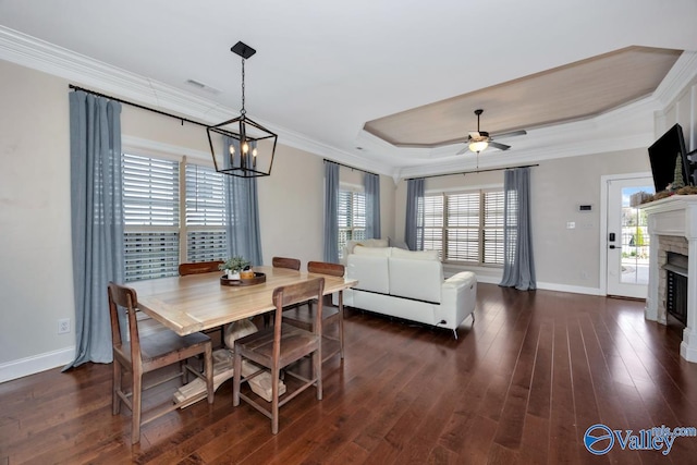 dining room featuring a raised ceiling, crown molding, dark hardwood / wood-style flooring, and ceiling fan with notable chandelier