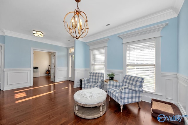 sitting room with a chandelier, crown molding, and dark wood-type flooring