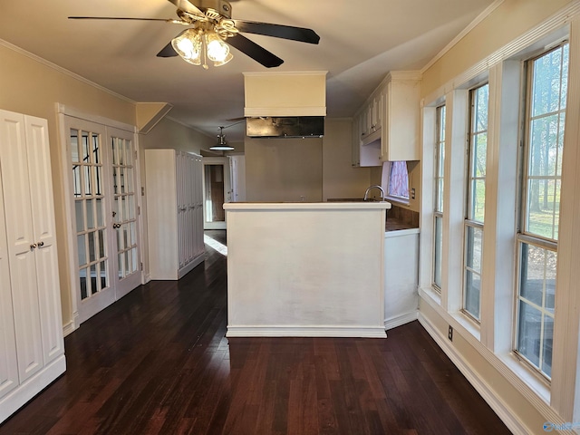 kitchen featuring ceiling fan, dark wood-type flooring, kitchen peninsula, crown molding, and white cabinets