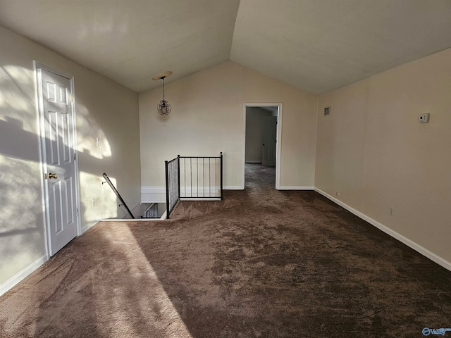 unfurnished room with dark colored carpet and vaulted ceiling