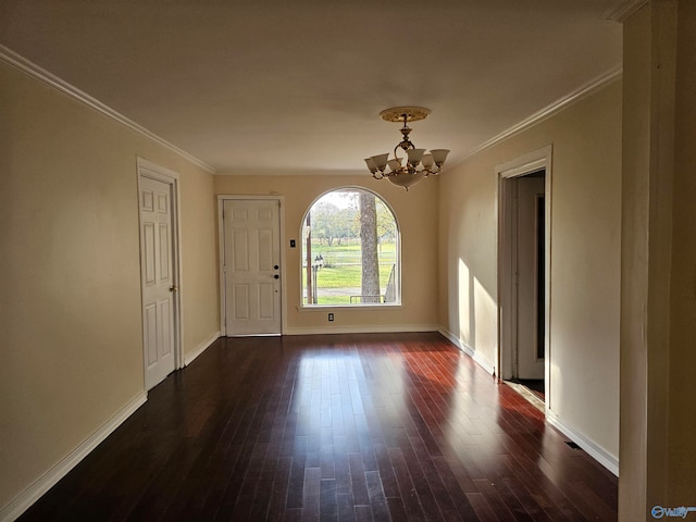 empty room with dark hardwood / wood-style flooring, ornamental molding, and a chandelier