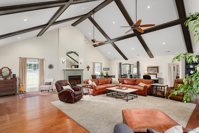 living room featuring light hardwood / wood-style flooring, beam ceiling, ceiling fan, and high vaulted ceiling