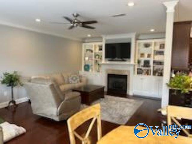 living room with ornate columns, dark wood-type flooring, and ceiling fan