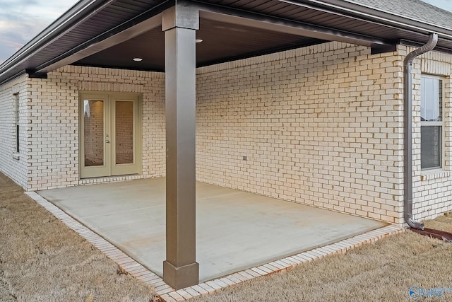 view of home's exterior featuring brick siding, a patio, and french doors