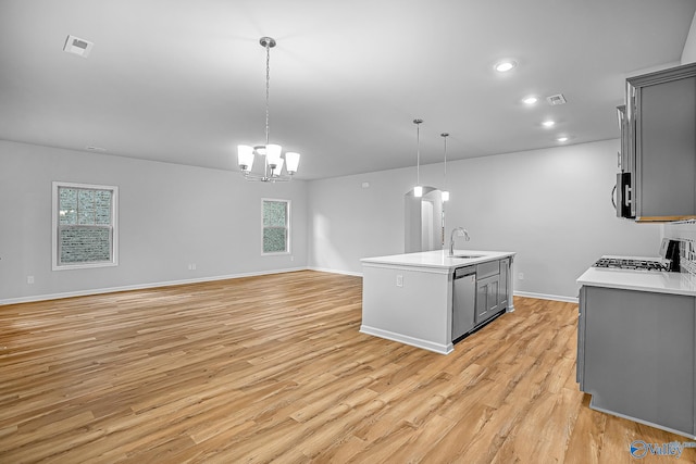 kitchen featuring light countertops, hanging light fixtures, gray cabinetry, appliances with stainless steel finishes, and a sink