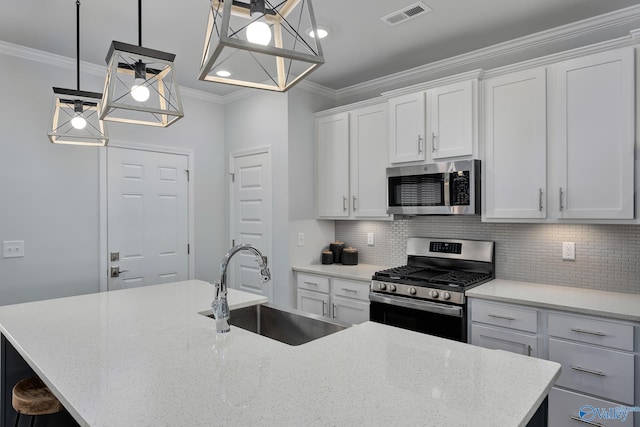 kitchen with sink, a kitchen island with sink, white cabinetry, stainless steel appliances, and decorative light fixtures