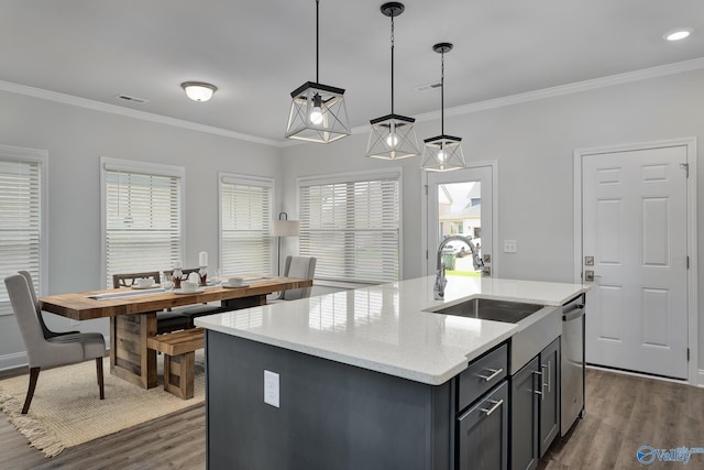 kitchen with pendant lighting, sink, light stone countertops, and an island with sink