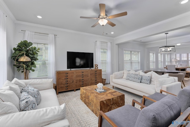 living room with ceiling fan with notable chandelier, a wealth of natural light, and ornamental molding