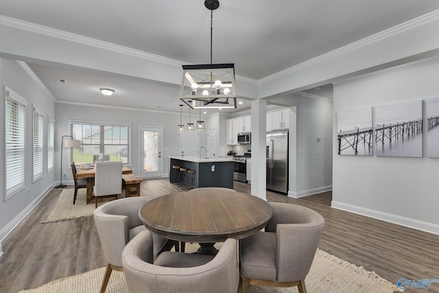 dining room with an inviting chandelier, sink, crown molding, and dark wood-type flooring