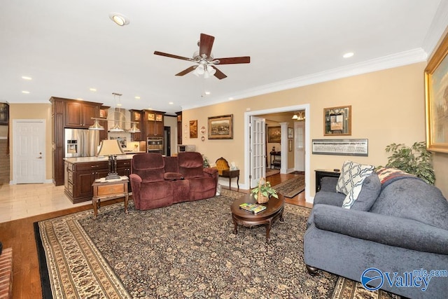 living room with ornamental molding, ceiling fan, and light hardwood / wood-style flooring