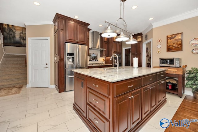 kitchen with stainless steel fridge with ice dispenser, sink, wall chimney range hood, a center island with sink, and decorative light fixtures