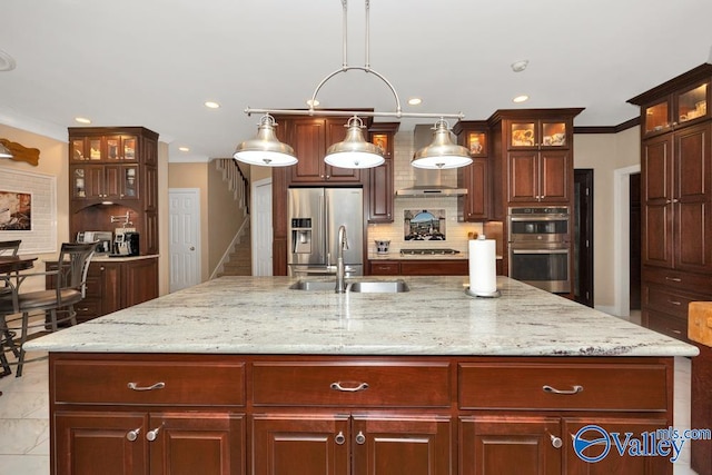 kitchen featuring hanging light fixtures, sink, a center island with sink, stainless steel appliances, and crown molding