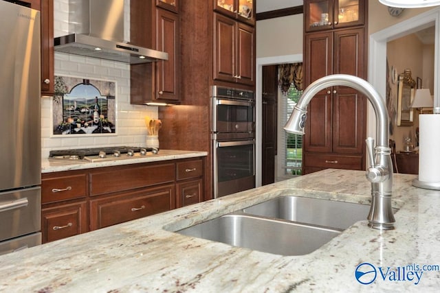 kitchen featuring decorative backsplash, light stone countertops, and wall chimney range hood