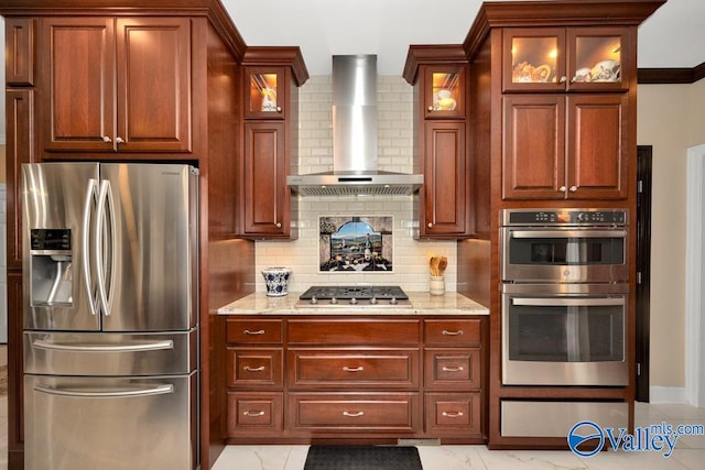 kitchen featuring light stone counters, stainless steel appliances, backsplash, and wall chimney range hood