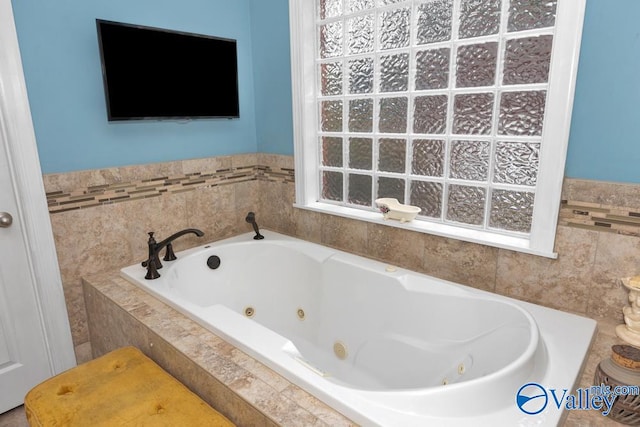 bathroom with tiled tub and plenty of natural light