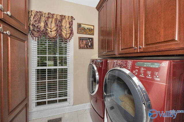 washroom featuring cabinets, light tile patterned floors, and washer and clothes dryer