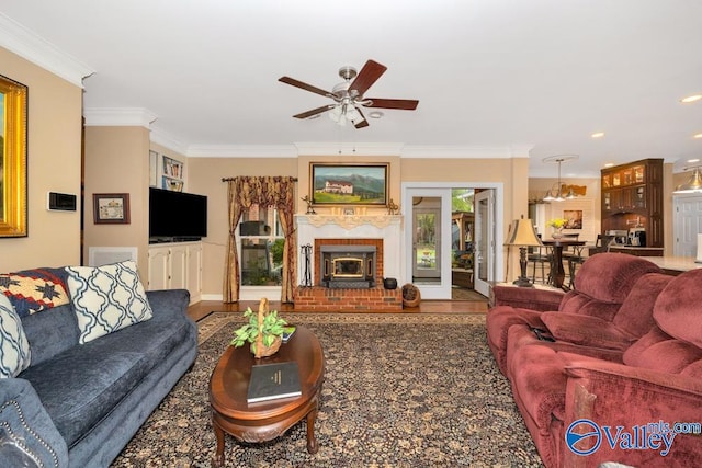 living room with ceiling fan, a fireplace, ornamental molding, and wood-type flooring