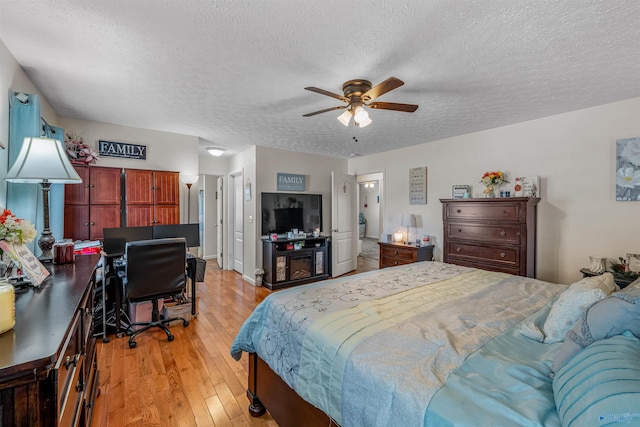 bedroom with light wood-style floors, ceiling fan, and a textured ceiling