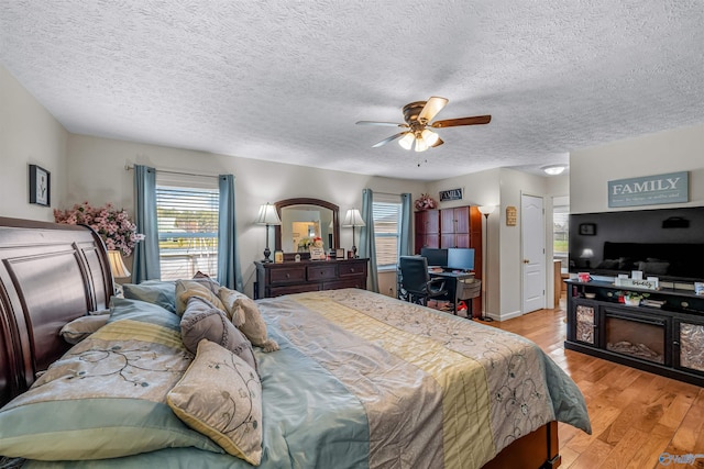 bedroom featuring a ceiling fan, baseboards, light wood finished floors, and a textured ceiling